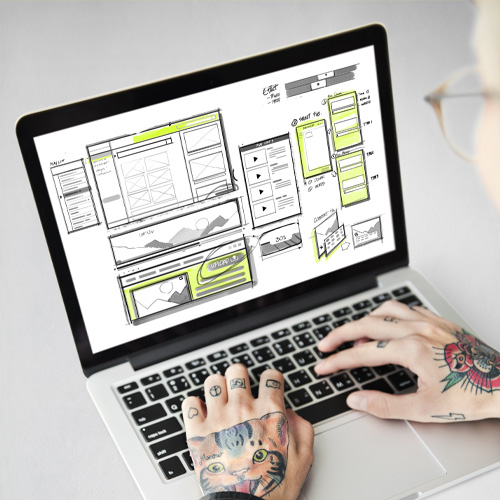 Webdesigner, der vor einem Laptop sitzt und eine Website erstellt.