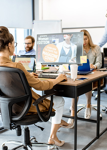 Bild von Mitarbeitern, die in einer Werbeagentur an Schreibtischen sitzen.