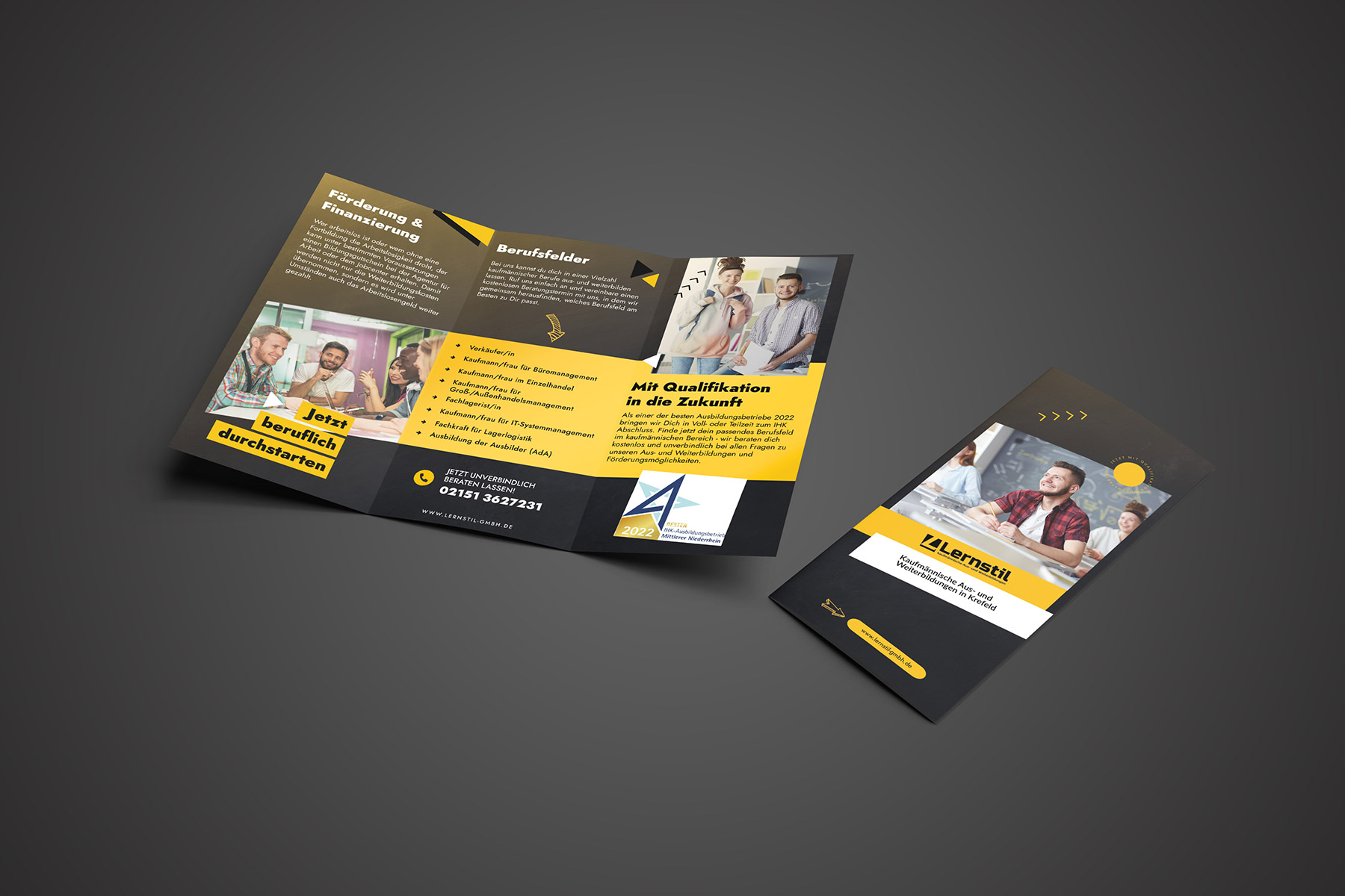 Geöffneter Falzflyer und ein geschlossener Falzflyer vor einem Hintergund mit dunkelgrauen Hintergrund.